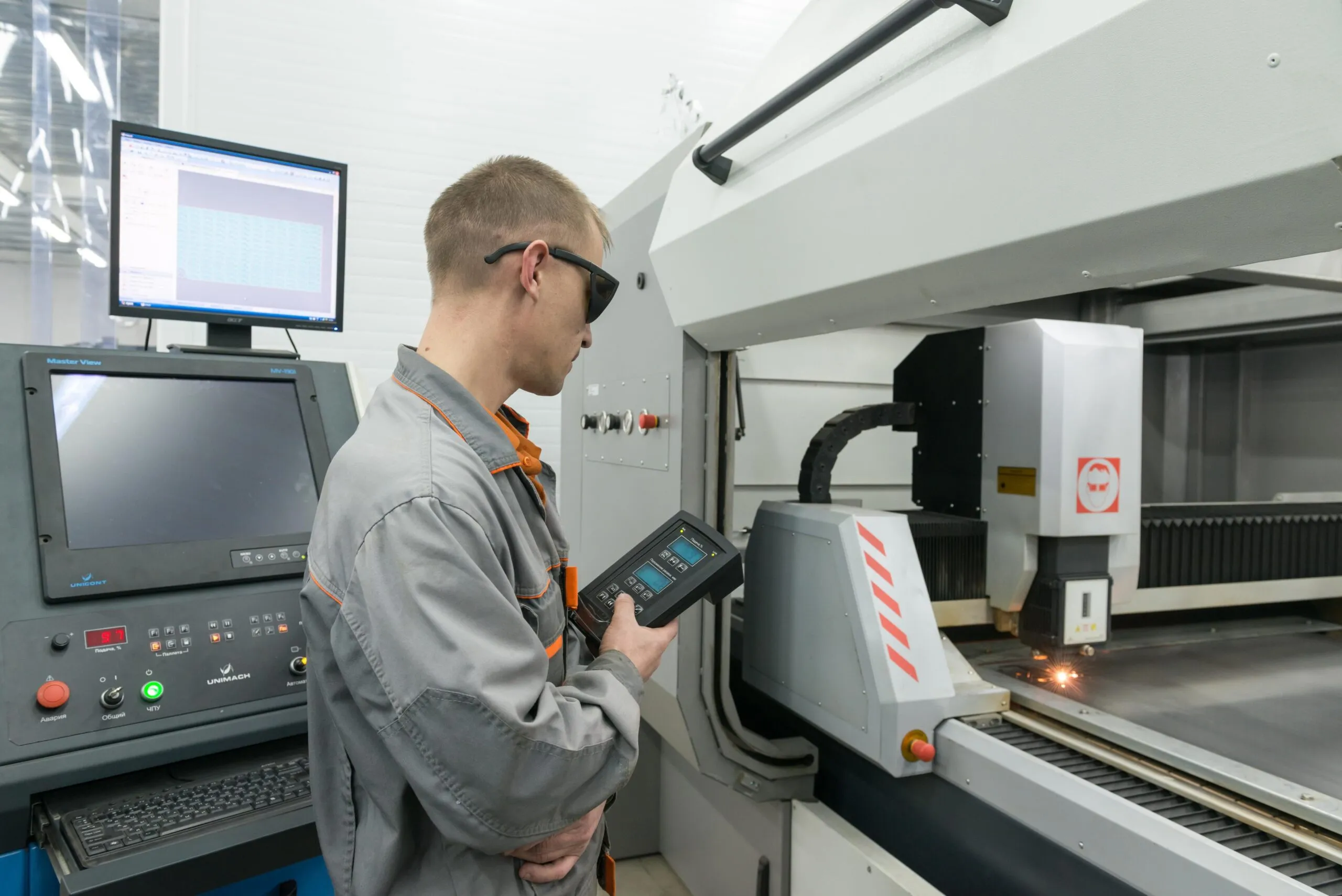 Un ouvrier travaillant sur une machine de découpe laser, découpant des pièces métalliques avec précision.